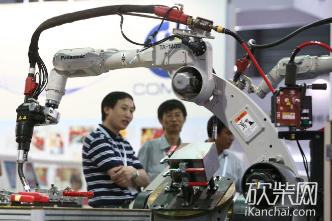 Visitors look at robot arms of Panasonic on display during the China International Robot Show 2013 in Shanghai, China, 2013.